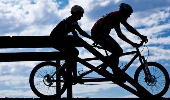 Silhouette of 2 people riding a tandem bike