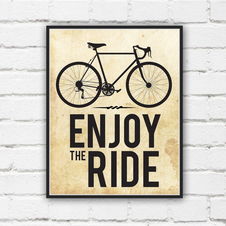 Enjoy the Ride in bold black text below an outline of a bicycle against a white brick wall