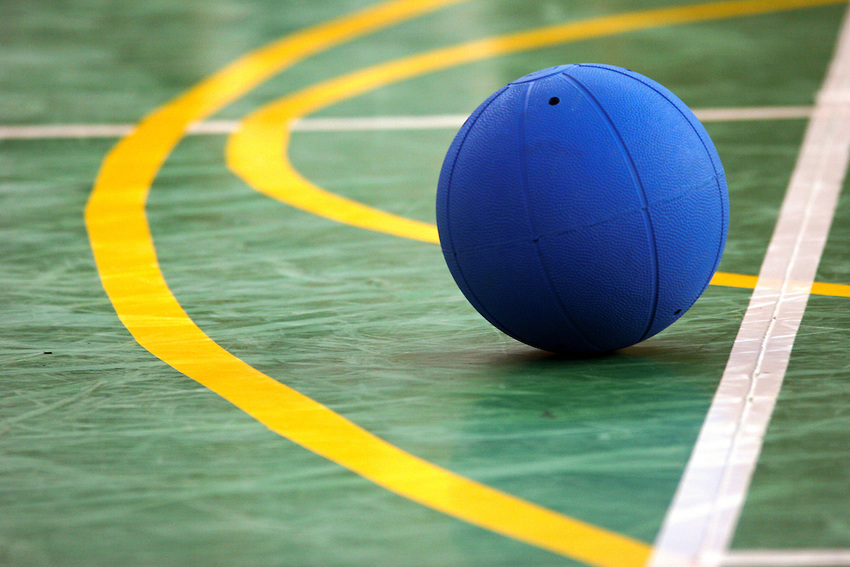 blue goalball on a green gym court floor